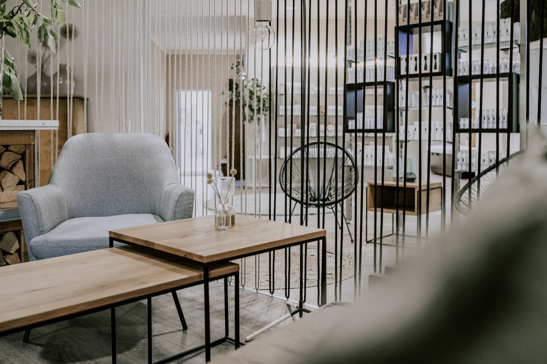 Lounge mit hellen Sesseln, Holztisch und Kaminholz